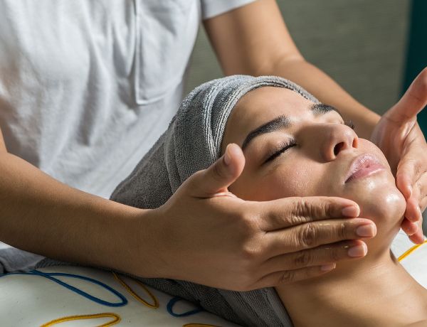 Frau erhält Gesichtsmassage mit Handtuch auf der Stirn – ästhetische Hautpflege im Sommer