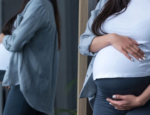 Frau hält ihren Babybauch fest