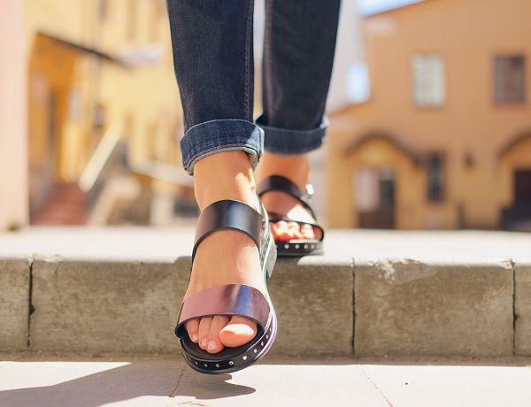 Frau in Sandalen läuft entspannt durch die Stadt und zeigt gepflegte Füße im Sommer in Berlin