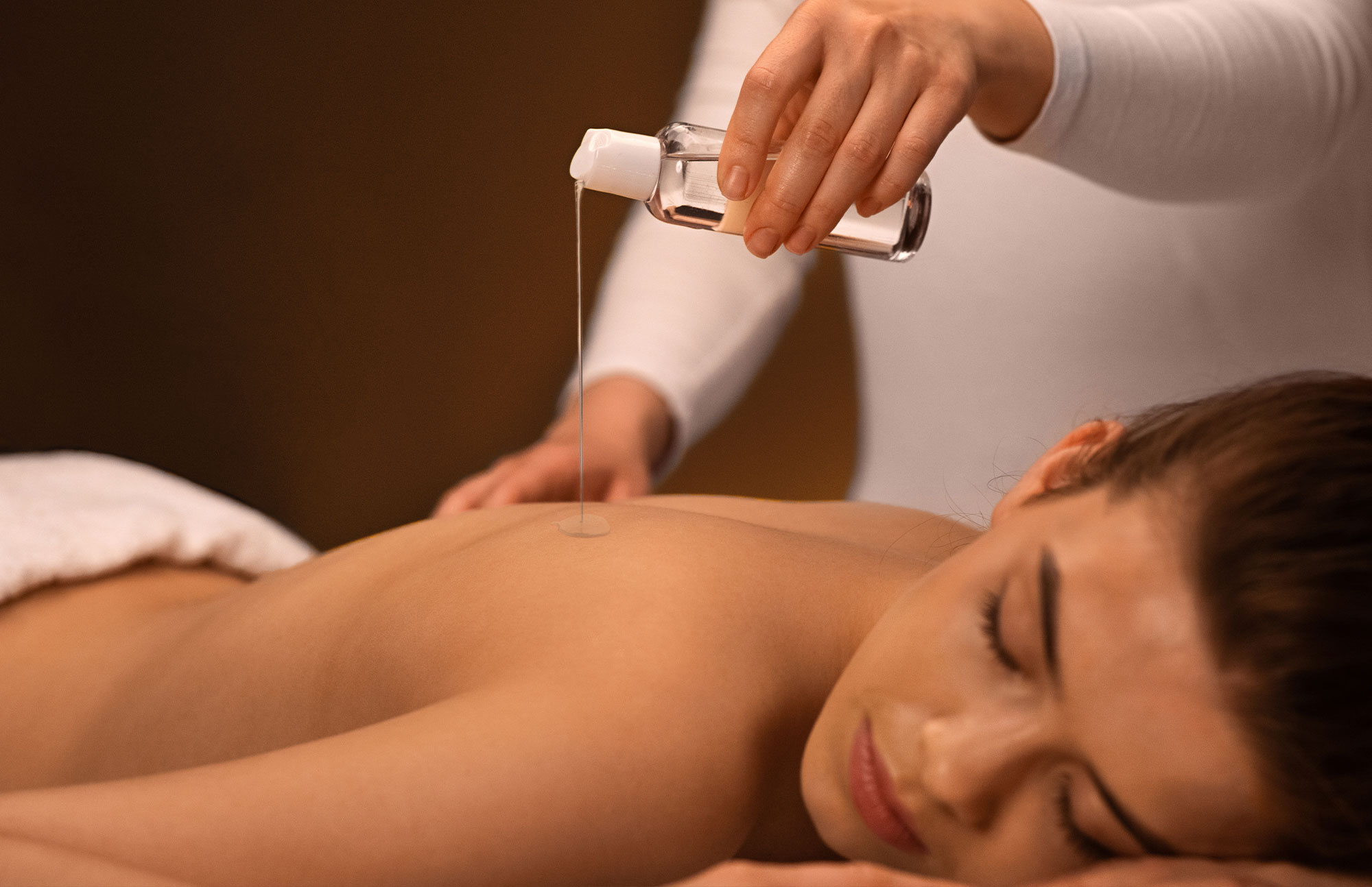 Frau liegt entspannt bei einer wohltuenden Aromamassage zur Stressbewältigung im Sommer