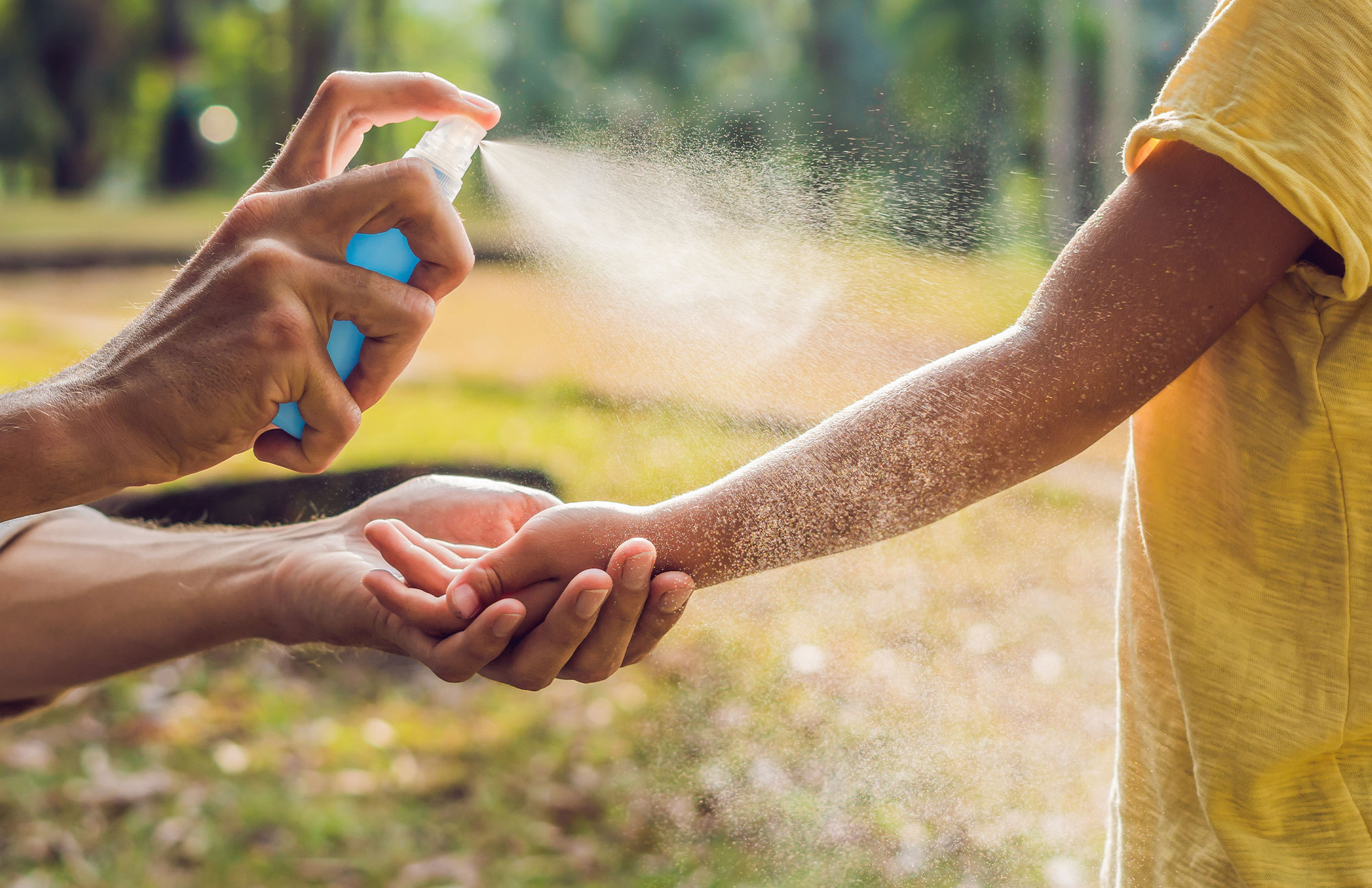 Hand wird mit Insektenspray eingesprüht zum Schutz vor Mücken und Zecken im Sommer