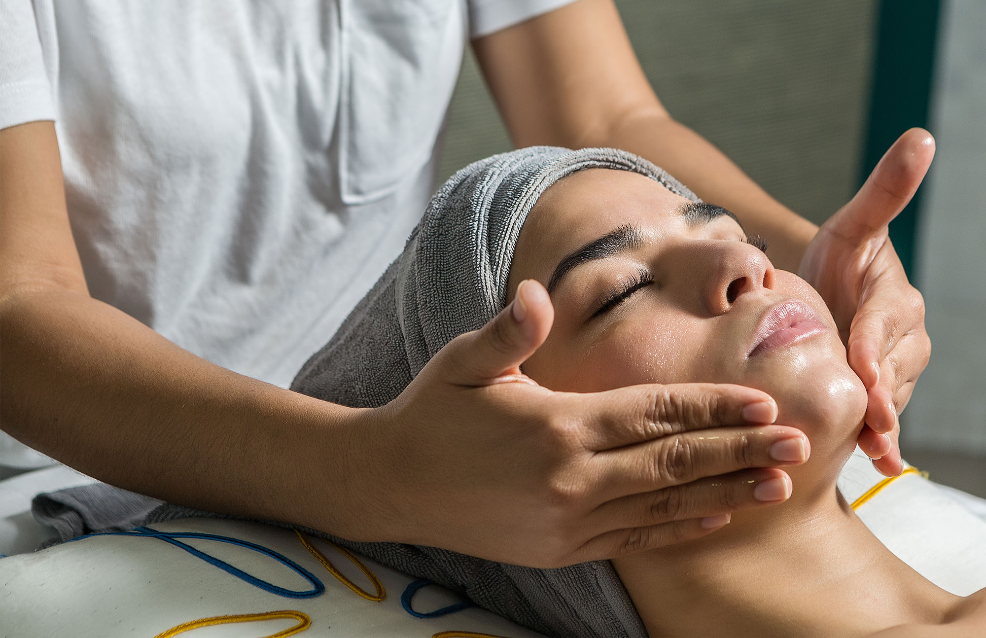 Frau erhält Gesichtsmassage mit Handtuch auf der Stirn – ästhetische Hautpflege im Sommer